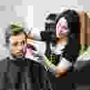 A woman is getting her hair cut by a man.