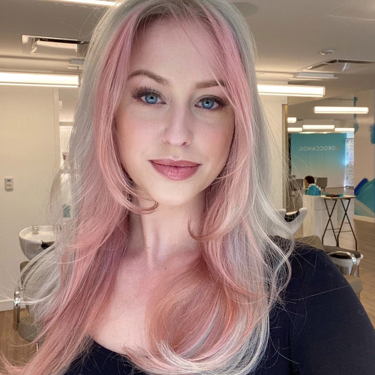 Woman with pink and gray hair smiling.